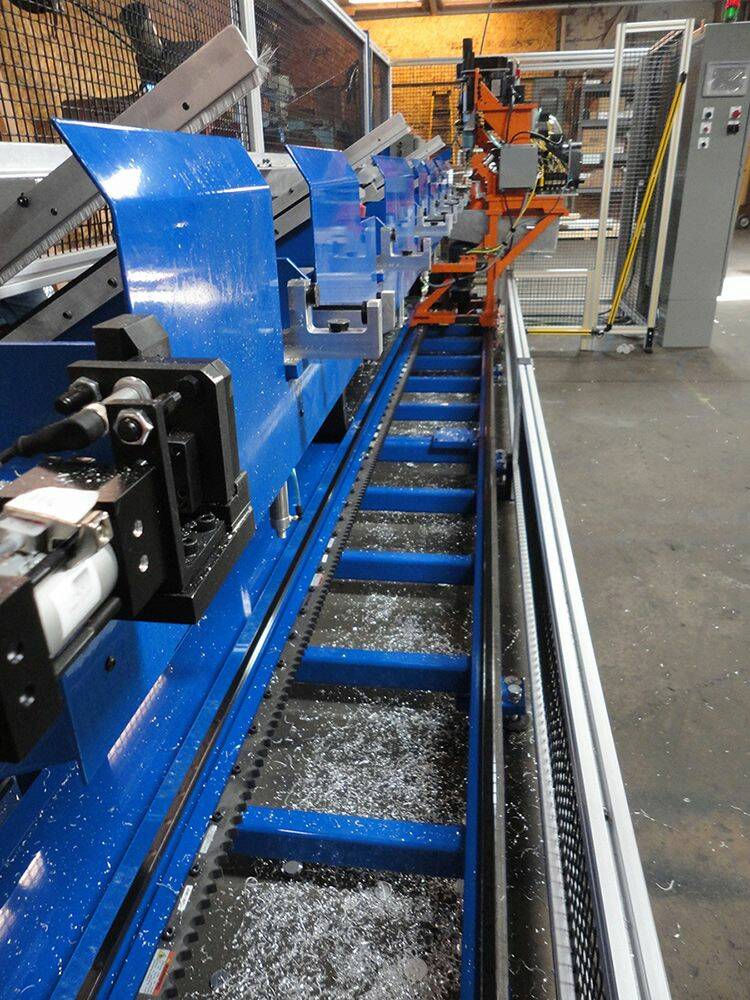 Vue de la machine d'alésage spécialement conçue pour le client. Le bâti de couleur orange est la tête d'alésage à déplacement linéaire, entraînée par le système de pignon crémaillère à rouleaux de Nexen logé dans la partie inférieure de la machine. Les copeaux d'aluminium résultant de l'usinage sont visibles dans le fond de la machine. © Lumco
